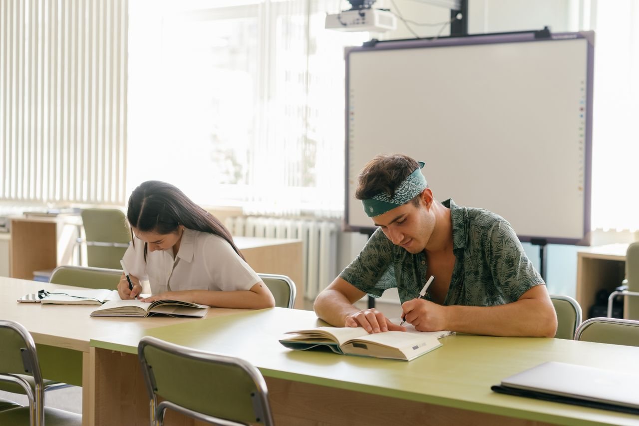 Free Two students focused on study in a bright, modern classroom. Stock Photo