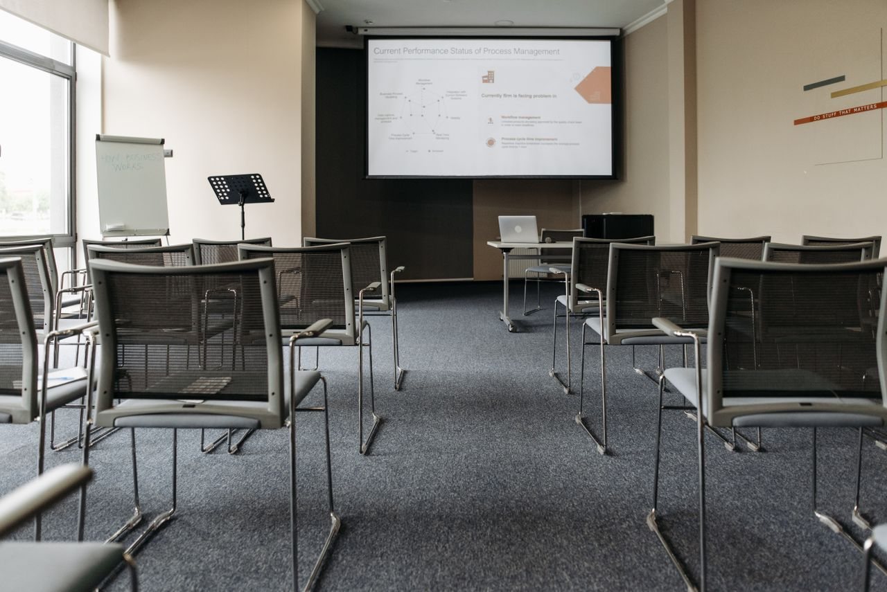 Free An empty conference room with chairs, a projector screen, and presentation setup. Stock Photo