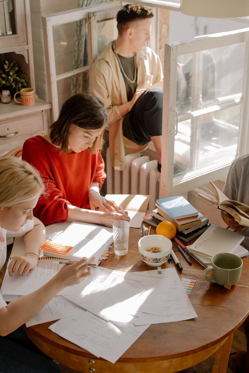 Free Group of college students studying in a sunlit room with books, papers, and a cozy atmosphere. Stock Photo